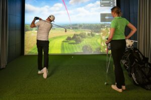 TrackMan Leinwand zeigt ein virtuelles Golfloch während einer Indoor Runde im GC Widukind Land.