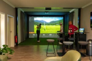 Gemütliche Indoor Golf Umgebung mit Simulator und Monitor im GC Widukind Land