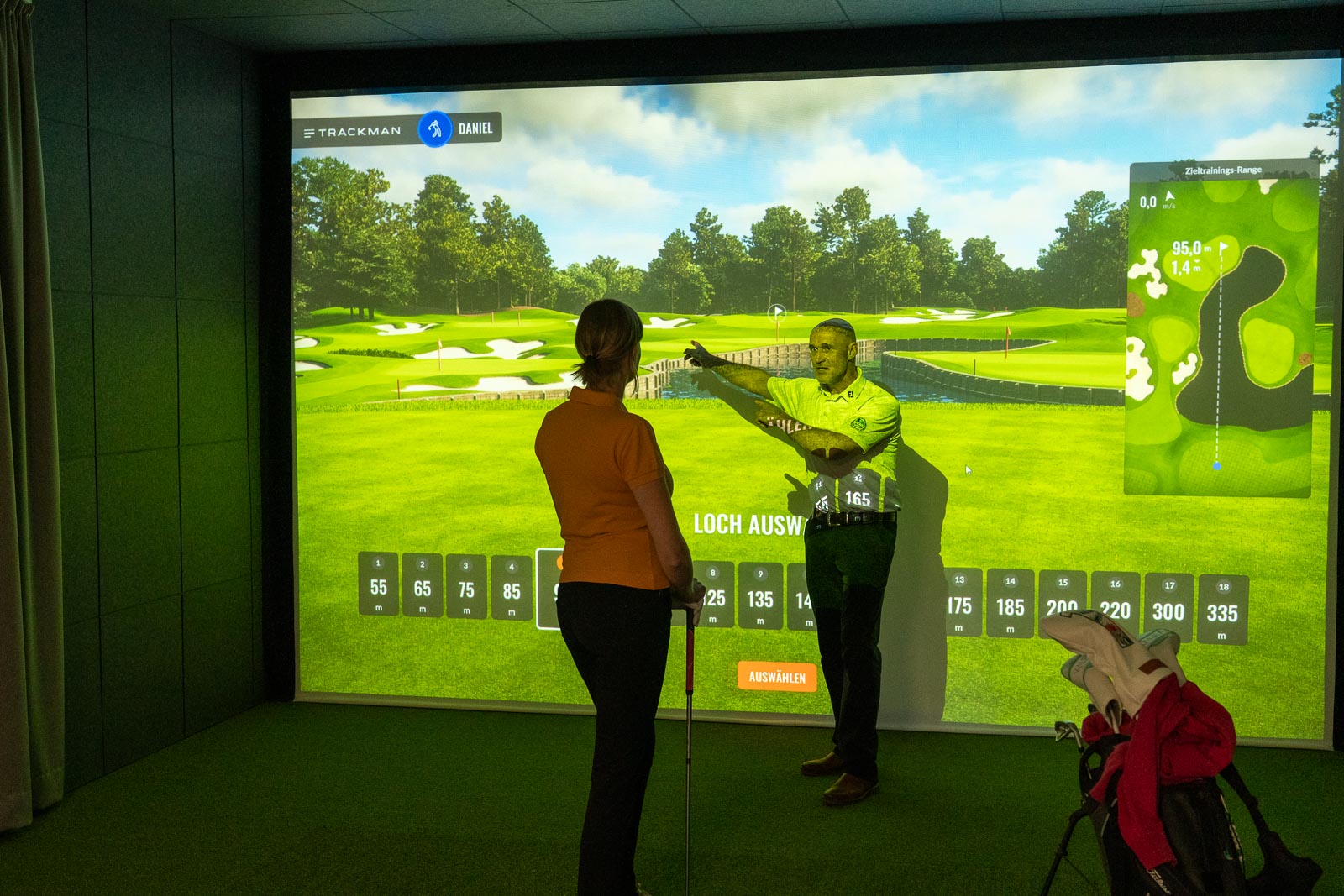 Spielerin betrachtet mit Pro Ihre TrackMan Daten während einer Indoor Golf Kurzspiel-Einheit