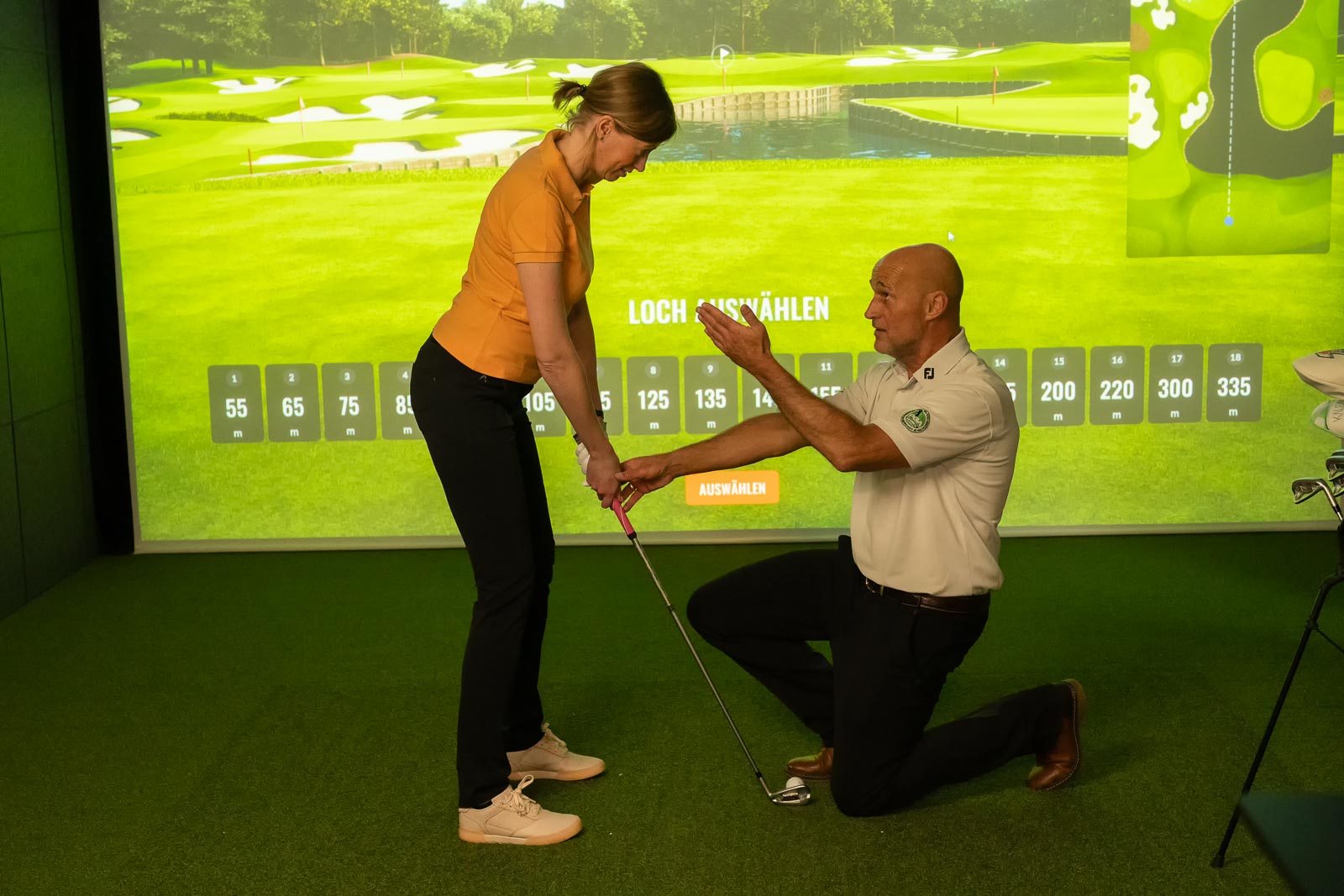 Golferin trainiert mit Pro Ihren Griff im TrackMan Simulator der Indoor Anlage