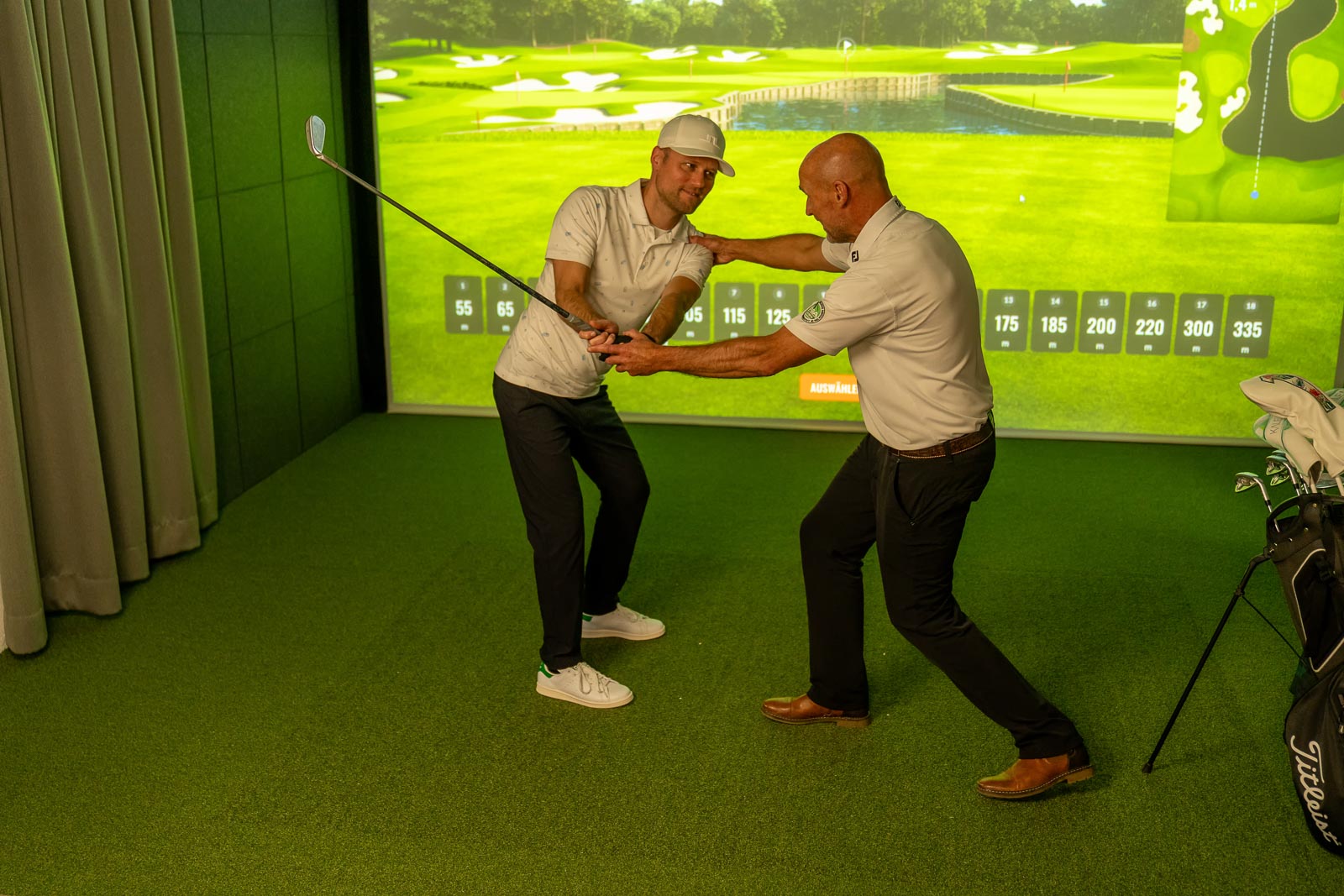 Golfer trainiert seinen Schwung mit Pro im TrackMan Simulator der Indoor Anlage